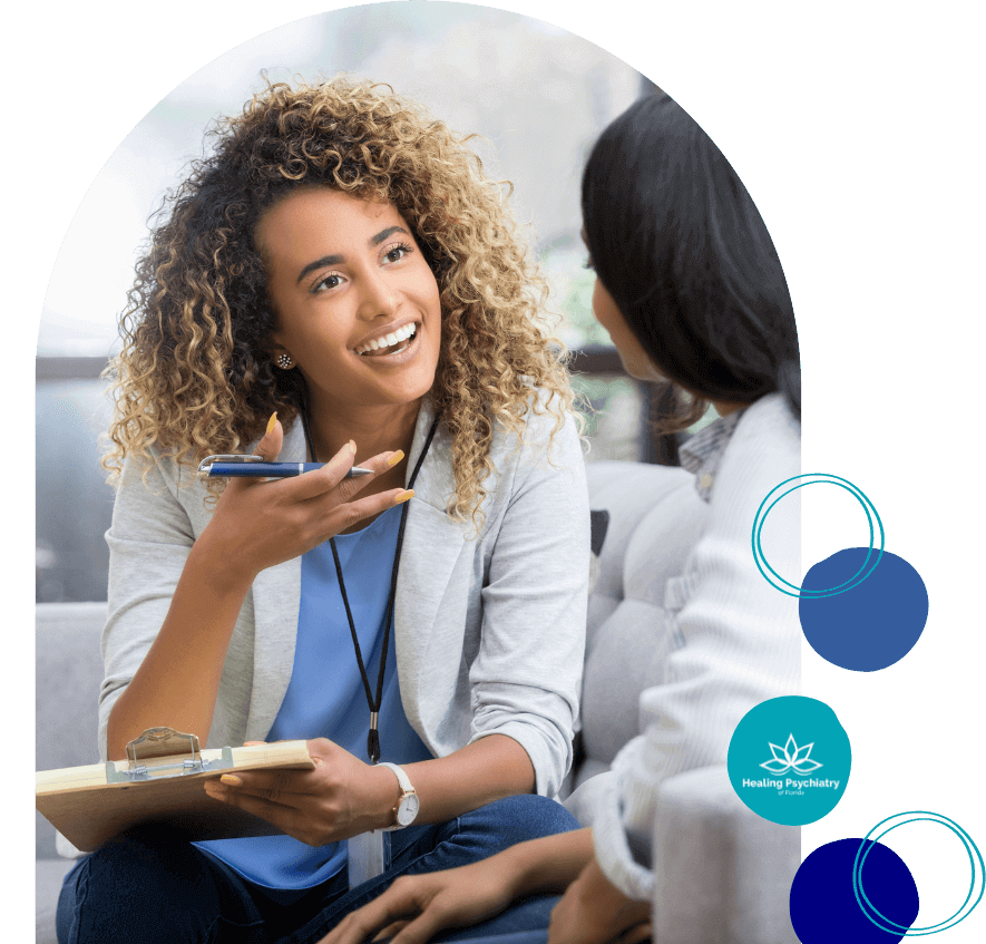 Compassionate therapist with curly hair smiles and listens intently to a patient during a session at Healing Psychiatry.