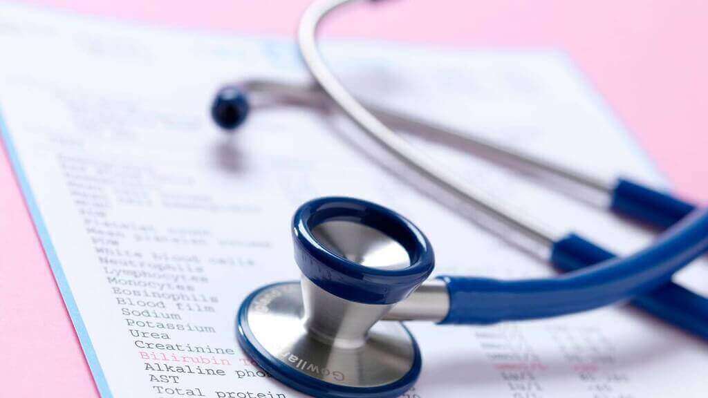 A stethoscope rests on a medical report with various test results