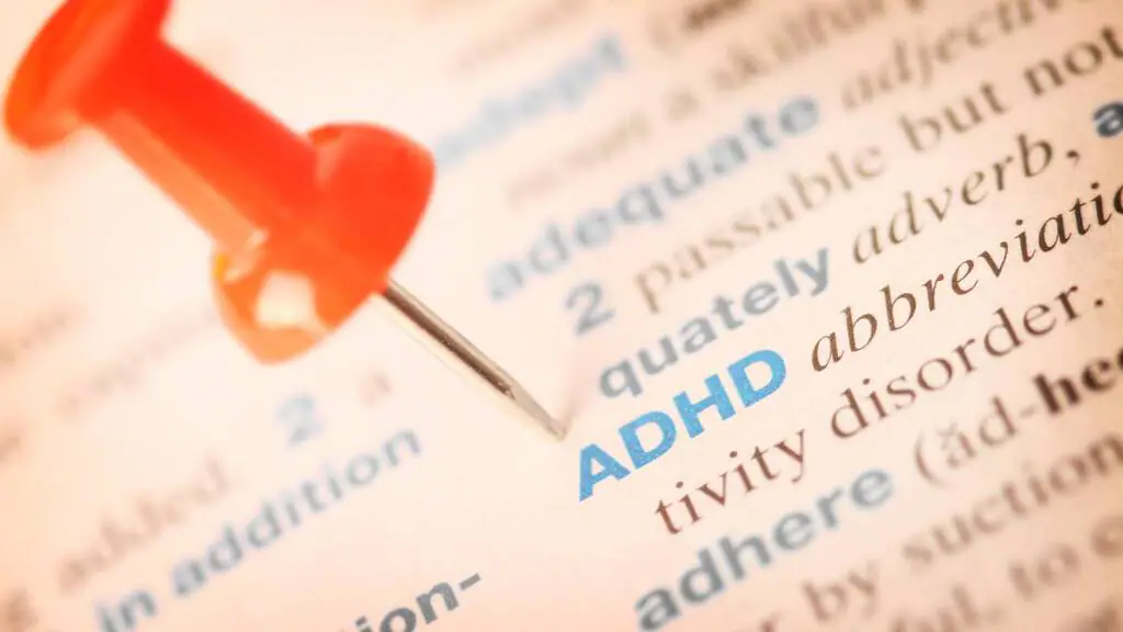 A red pushpin marks the word "ADHD" in blue text in a dictionary or glossary