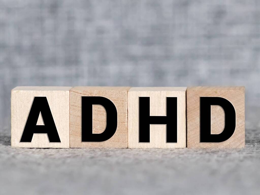 Wooden blocks spell out "ADHD" in bold black letters against a gray background