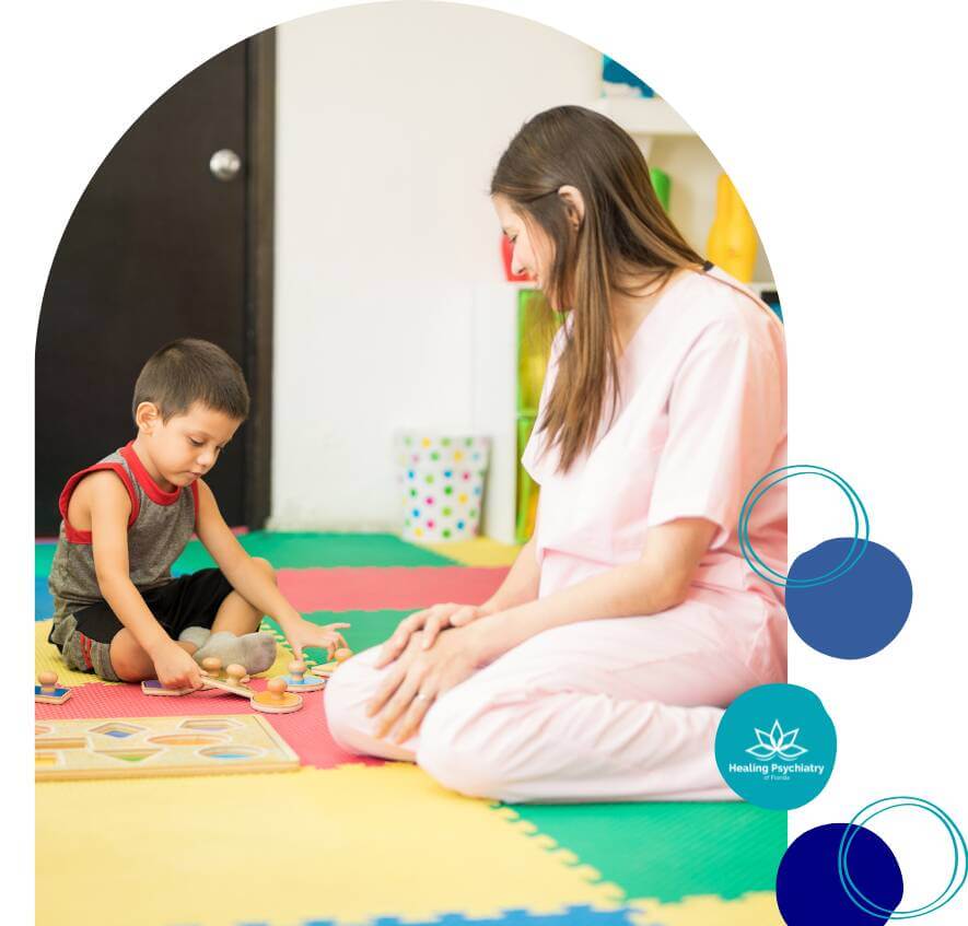 A young boy engaging in a therapy session with a counselor, playing with a wooden puzzle on a colorful playroom floor.