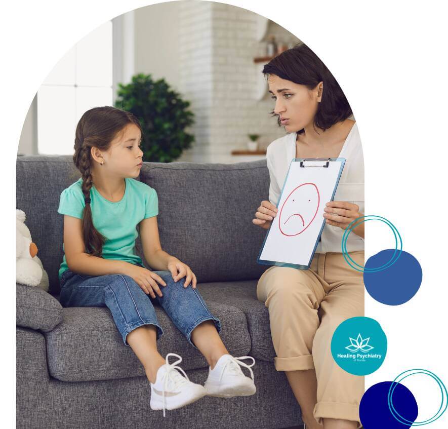 adhd kids A therapist shows a drawing of a sad face to a young girl during a therapy session, as the child looks attentively.