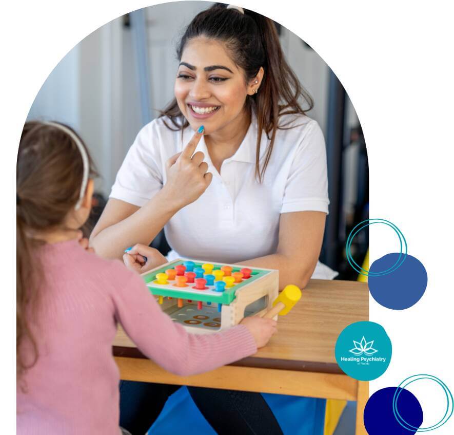 A smiling female therapist engaging in a playful therapy session with a young girl, using a colorful toy activity board during a child therapy session at Healing Psychiatry of Florida.