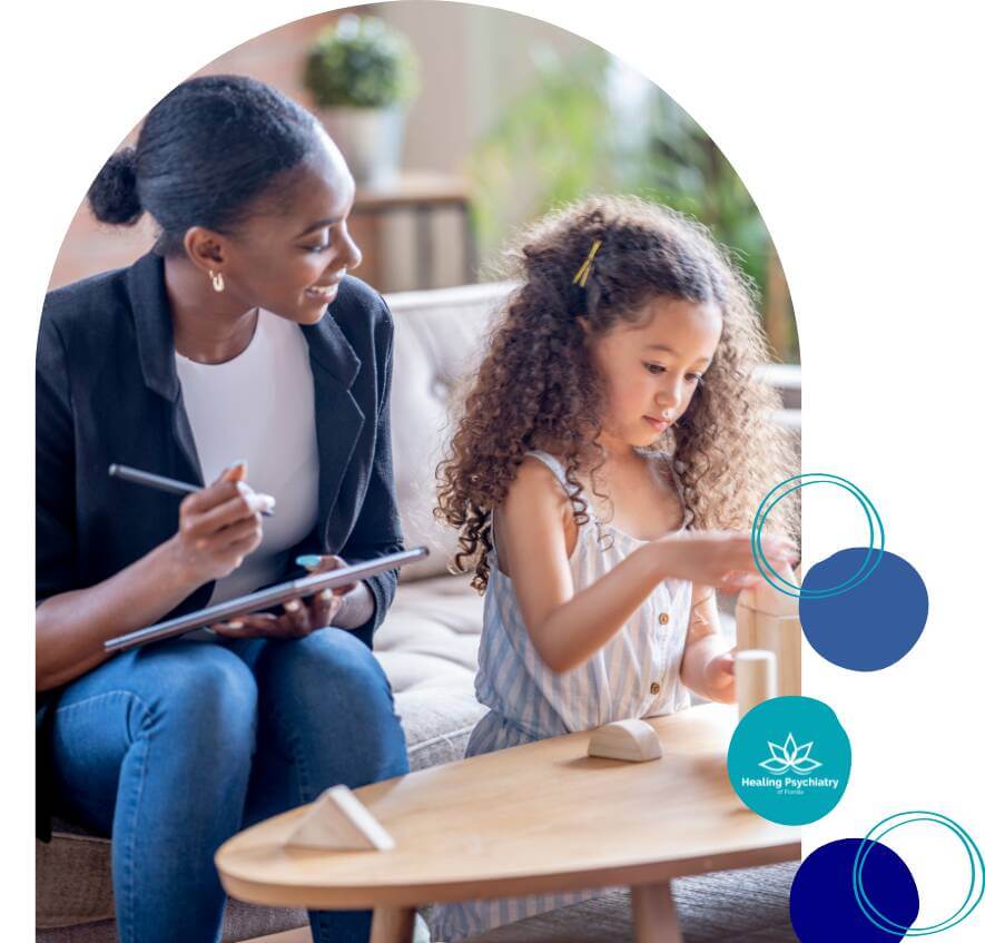 A therapist interacts with a young child during a children's therapy session, providing support while the child plays with toys.