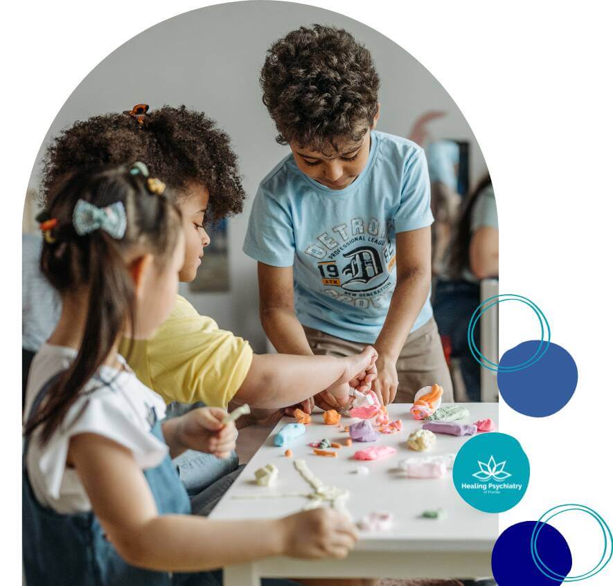 ocd child (1) Three children playing with colorful clay at a table, engaging in a creative activity together.