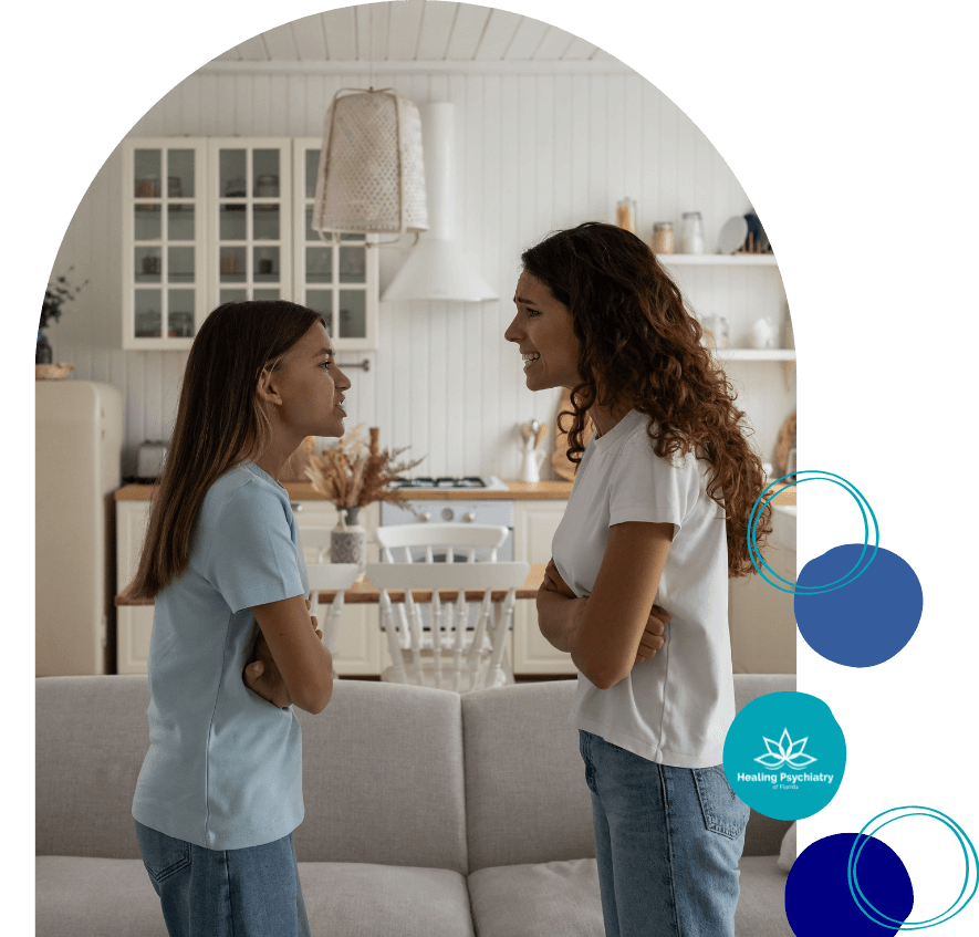 A mother and daughter stand facing each other in a kitchen, engaged in a tense conversation.